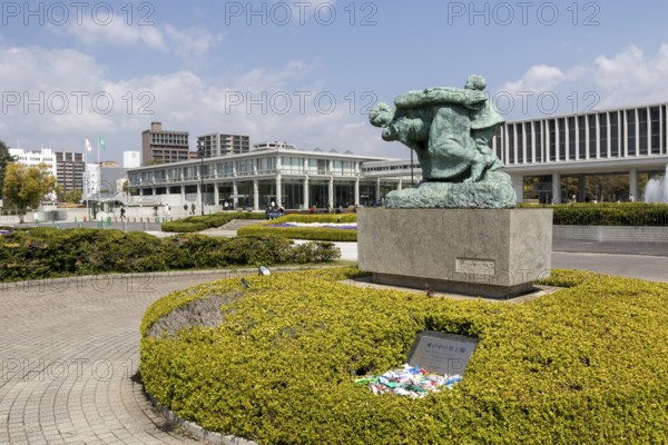 Statue of mother and children in the storm, bronze statue by the artist Shin Hongo in front of the Hiroshima Peace Museum, landmark, UNESCO World Heritage Site, peace memorial and memorial to the victims of the atomic bombing of Hiroshima in the Peace Park, Naka Ward, Hiroshima, Japan