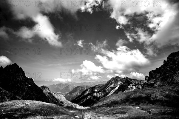 Dramatic black and white image of a rocky mountain landscape under a cloudy sky. Kleinwalsertal Vorarlberg Austria