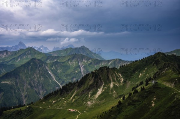 Green hills and mountains under a cloudy sky with far-reaching views. Kleinwalsertal Vorarlberg Austria