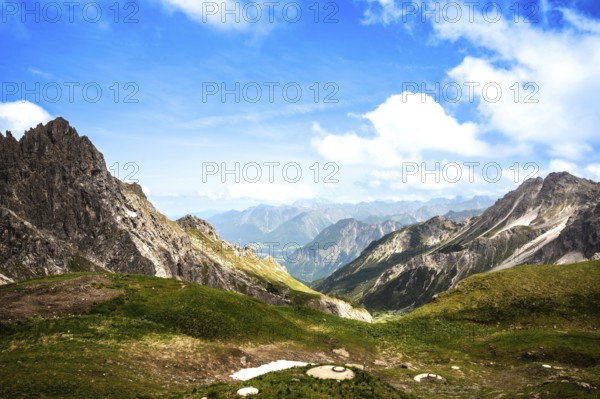 Sweeping views over green valleys and rocky mountains under a clear blue sky. Kleinwalsertal Vorarlberg Austria