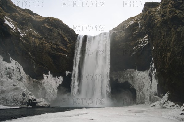 The mighty Skogafoss waterfall in winter. Roaring masses of water meet ice and rock. Skogar, Rangarping eystra, Iceland
