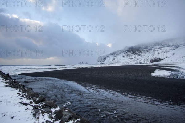 A black beach cuts through white stilts. A coastline like a painting. Renisfjara, Iceland