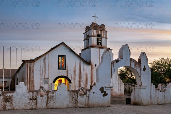 Illuminated church in the evening with warm light and ecclesiastical cross, The church of San Pedro de Atacama in Chile