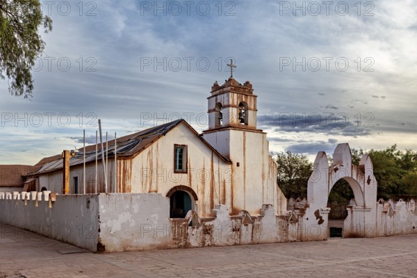 Rustic church under a cloudy sky, striking cross and historic architecture, The church of San Pedro de Atacama in Chile