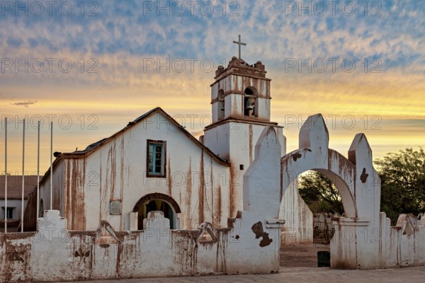 Church at dusk with warm colours and a striking church cross in the foreground, The church of San Pedro de Atacama in Chile
