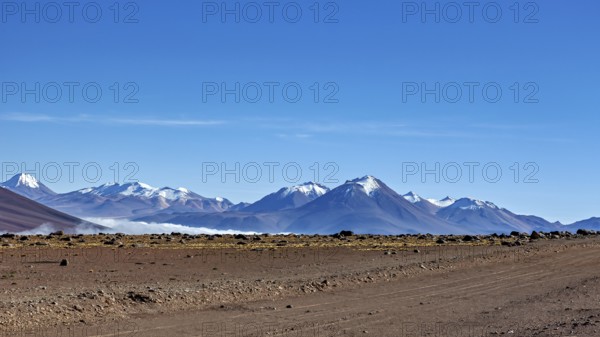 Vast dry desert landscape with snow-capped mountains and clear blue sky, The landscape at San Pedro de Atacama in Chile
