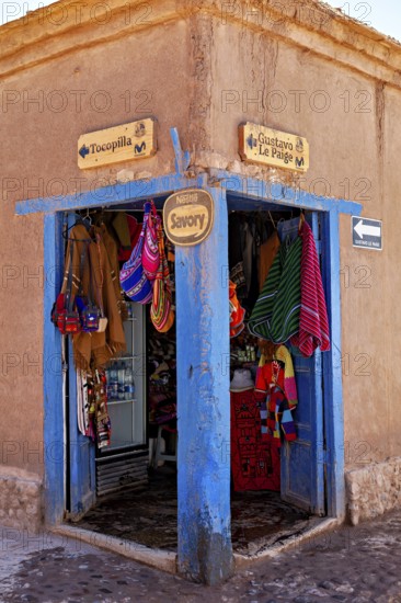 Corner of a souvenir shop with colourful textiles and handicrafts. Rustic style with striking blue door frame, The market with souvenir shops in San Pedro de Atacama in Chile