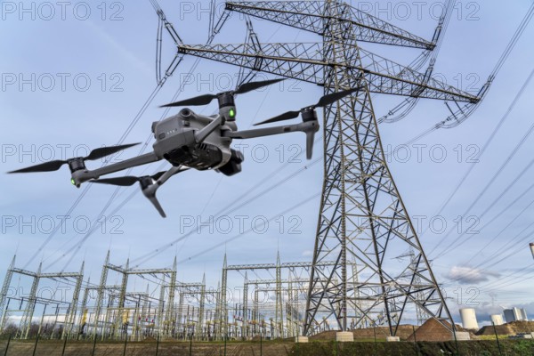 Symbolic image, photomontage, reconnaissance, spying with drones in industrial plants, critical infrastructure, drone flies towards an industrial complex, power plant, spying by camera drones