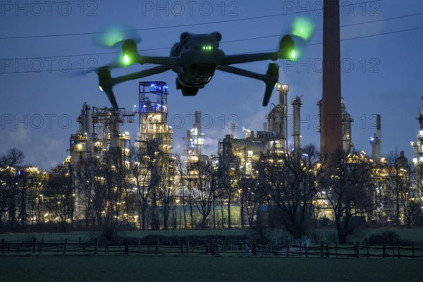 Symbolic image, photomontage, reconnaissance, spying with drones in industrial plants, critical infrastructure, drone flies towards an industrial complex, chemical plant, spying by camera drones