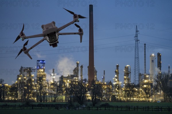Symbolic image, photomontage, reconnaissance, spying with drones in industrial plants, critical infrastructure, drone flies towards an industrial complex, chemical plant, spying by camera drones