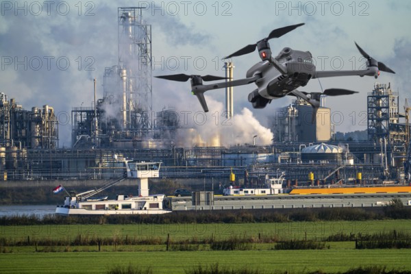 Symbolic image, photomontage, reconnaissance, spying with drones in industrial plants, critical infrastructure, drone flies towards an industrial complex, chemical plant, spying by camera drones