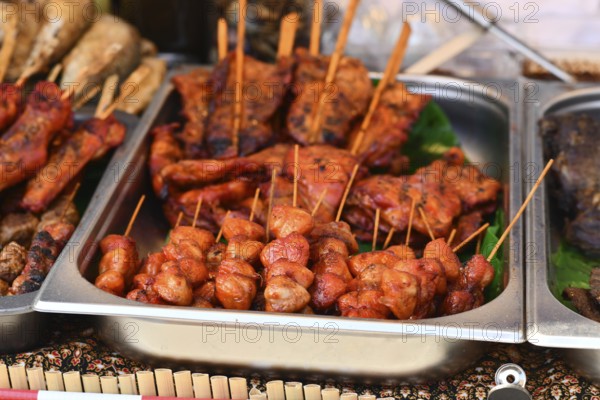 Grilled red marinated Thai meat skewers at street food market