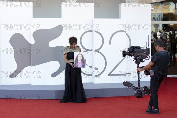 Venice, Italy - 3 September 2025: Kaouther Ben Hania with a portrait of five-year-old Palestinian girl Hind Rajab, who was killed by the Israeli army in the Gaza Strip in January 2024, during the red carpet of - The Voice Of Hind Rajab - during the 82nd Venice International Film Festival