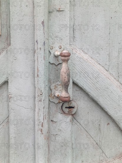 Fragment of a gray old wooden door with a handle