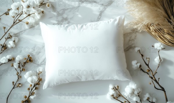 A white pillow on a marble surface framed by cotton branches with soft ambient lighting. AI generated