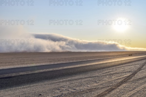 Abandoned area with dusty dirt road and some fog at evening time in Namibia
