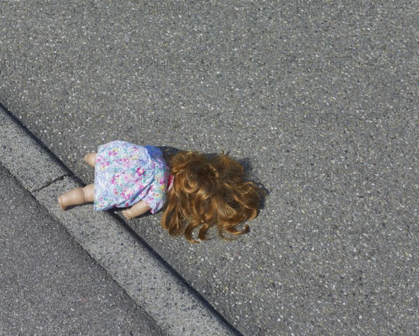 A doll lies on road surface in sunny ambiance