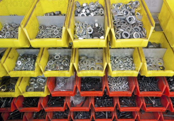 Full frame industrial background showing yellow and red boxes filled with lots of various screws and nuts