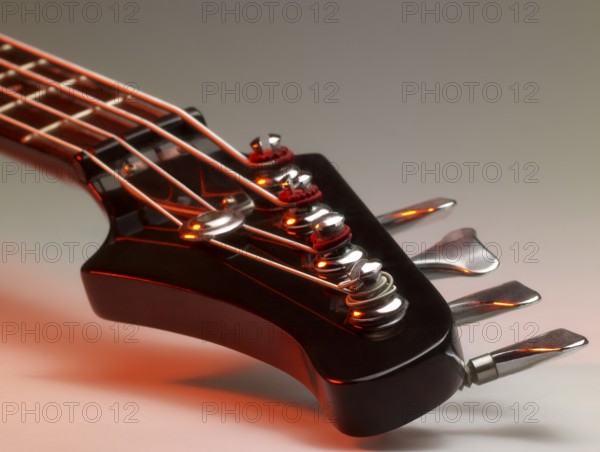 Detail of a bass guitar with red light in grey back