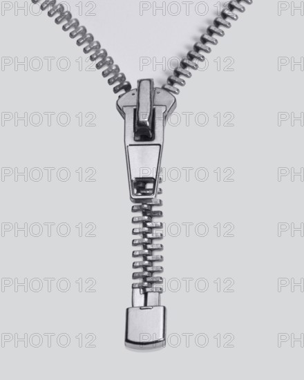 Studio photography of a long zipper half closed, in light back