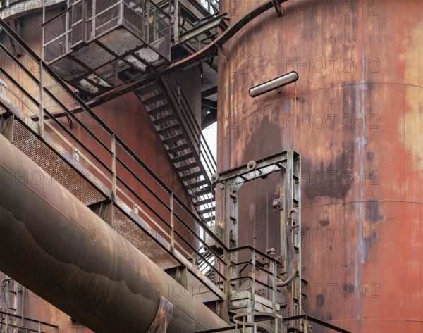Weathered rundown industrial scenery with old corroded steel girders, stairs and metal tubes
