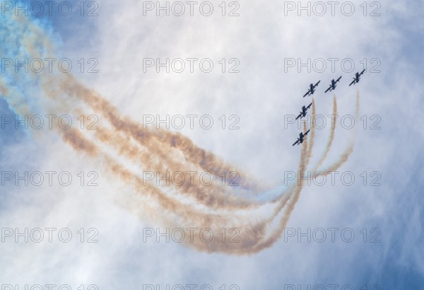 Air show of the Frecce Tricolori aerobatic team of the Italian Air Force with colored smoke trails in front of partly clouded sky