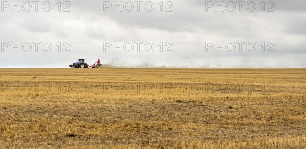 Stormy farmland scenery showing a Tractor on a stubble field in Hohenlohe, an area in Southern Germany at late summer time