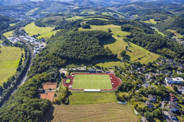 Aerial view, football stadium and athletics stadium, stadium at the Habuche and tennis court TC Grevenbrück 1975, hilly landscape and forest, on the left the commercial area Zur Brücke, Grevenbrück, Lennestadt, Sauerland, North Rhine-Westphalia, Germany, DE, Europe, football, football field, football stadium, commercial enterprise, commercial area, commercial area, commercial property, commercial park, commercial site, commercial use, industrial area, industrial site, Kirchhundem, aerial view, aerial photography, aerial photography, sports facility, sports field, tennis, tennis facility, tennis court, tennis courts, tennis club, overview, bird's-eye view, birds-eyes view, overview