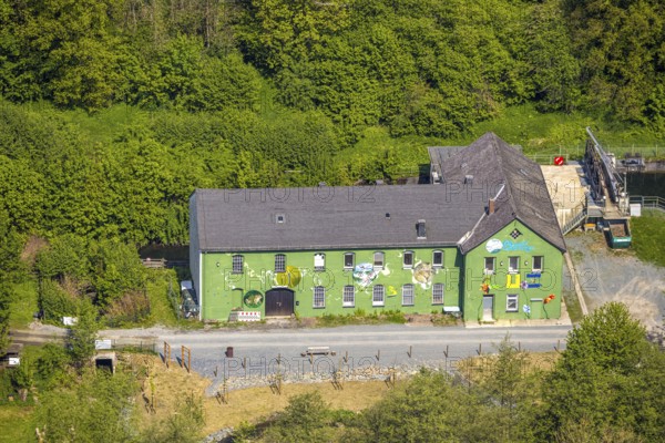 Aerial view, Altes Wasserkraftwerk Alfert, NaturRanger e.V., and green house painted with animals and plants, Ostwig, Bestwig, Sauerland, North Rhine-Westphalia, Germany, old hydroelectric power station, Alfert, painted house, green house, plants, animals, art, mural, building, architecture, nature, environmental protection, landscape, rural, wooded, picturesque, historic buildings, conscious decoration, culture, environment, bird's eye view, village, bank, river, energy, sustainability