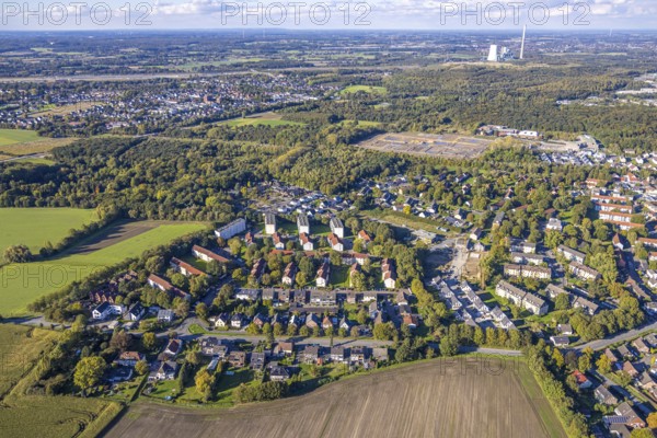 Aerial view, multi-family terraced houses on Berliner Straße, residential area local view district Weddinghofen, construction site AWO Kita Lippestrolche kindergarten, behind construction site for new forest settlement on the former Grimberg 3/4 mine site, Bergkamen power station, distant view and blue sky with clouds, Weddinghofen, Bergkamen, Ruhr area, North Rhine-Westphalia, Germany