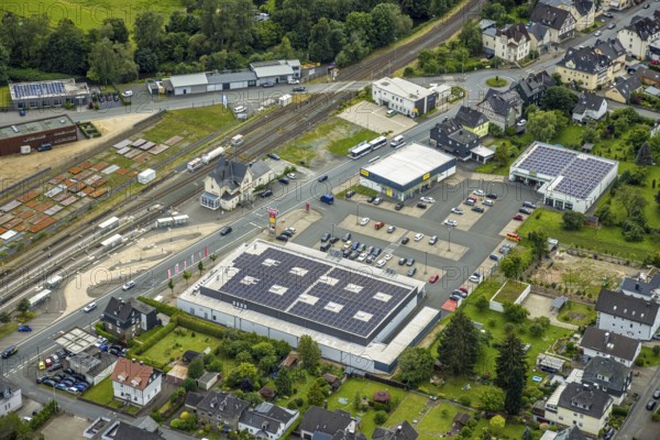 Aerial view, Bahnhofstrasse shopping centre with Rewe supermarket and solar roof, Takko fashion and K+K shoes, Bad Laasphe railway station and station building, new police station, Bad Laasphe, Wittgensteiner Land, North Rhine-Westphalia, Germany, architecture, railway station, station building, Bahnhofstrasse, drone shot, shopping district, shopping centre, retail, energy, development, building, shops, infrastructure, K+K shoes, sustainability, new building, perspective, police station, Rewe supermarket, solar system, solar roof, city, urban, Takko Fashion, transport links, renewable energies, modern, urban landscape, public space