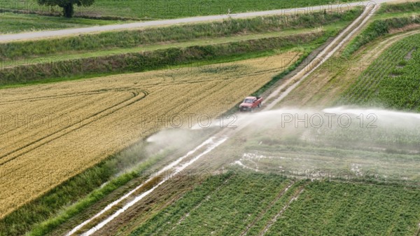 Agricultural irrigation using a rain gun sprinkler system for soybean cultivation in the Po Valley Italy during springtime providing essential water for crop growth and a healthy harvest