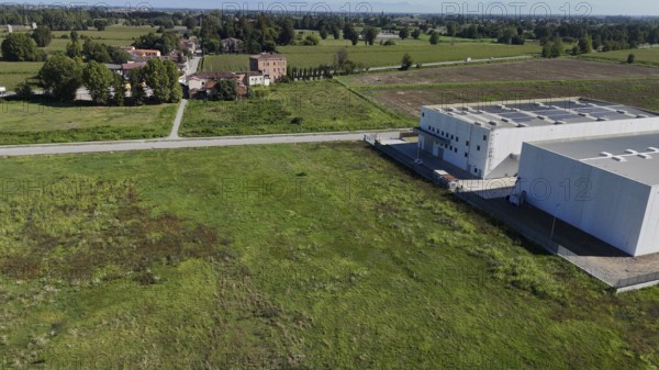 Modern industrial facility development in the Italian countryside showcasing infrastructure growth and technological advancement in the Lombardy region creating opportunities for data center and cloud storage expansion