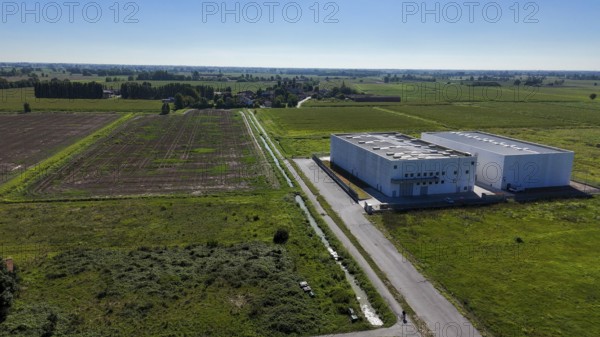 Modern data center facility situated in a rural landscape of Lombardy Italy surrounded by agricultural fields and infrastructure providing secure cloud storage solutions for global enterprises and businesses