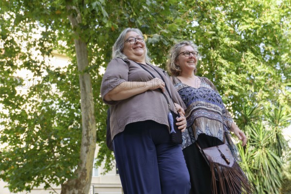 Two cheerful senior women enjoying a walk together in a park, celebrating their love, diversity, and lgbtq pride