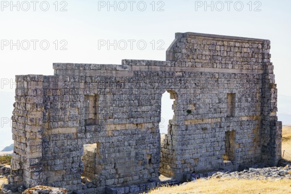 08/21/2025 Ronda, Malaga, Spain Main facade of the ruins of the Roman amphitheater of Acinipo with a white sky in the background