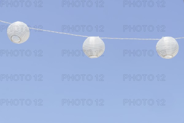 White paper lanterns decorating an outdoor space, adding a festive touch against a clear blue sky