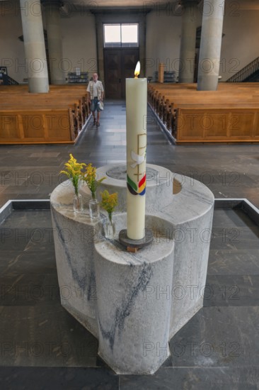 The Roman Catholic parish church of St Martin, interior with baptismal font, candle and floral decorations, Dornbirn, Vorarlberg, Austria