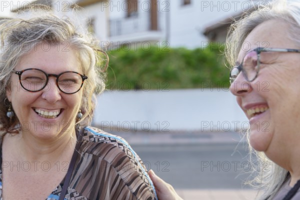 Two cheerful senior women enjoying each other's company outdoors, sharing laughter and happiness