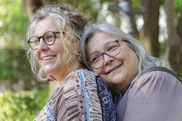 Happy mature lesbian couple enjoying a tender moment together in nature, celebrating their love and lgbtq pride