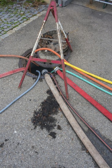 Water hoses and warning triangle on tarmac above open gully, Circus-Krone, Kempten, Allgäu, Bavaria, Germany