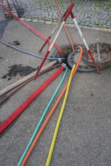 Water hoses and warning triangle on tarmac above open gully, Circus-Krone, Kempten, Allgäu, Bavaria, Germany