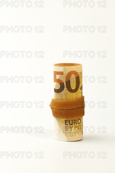Close-up of fifty euro banknotes rolled up and secured with a rubber band, symbolizing savings, investment, or financial security