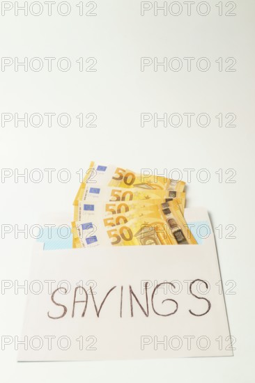 Envelope containing fifty euro banknotes and the word savings represents the concept of accumulating money