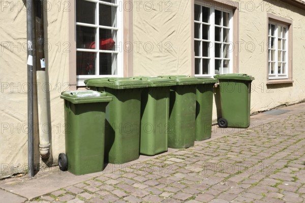 Green wheelie bins placed on residential street in Germany for waste collection