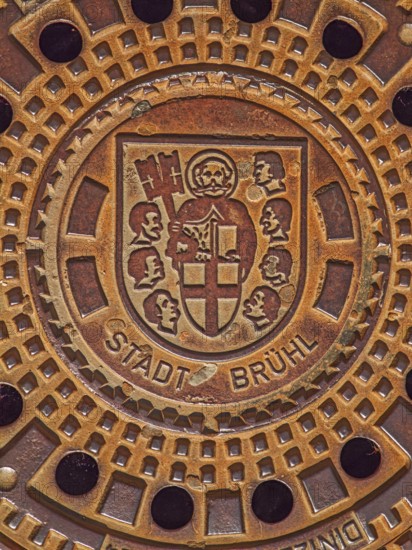 Round manhole cover with city coat of arms, Cologne collegiate cross, St Peter in cloak, key, book, heads of seven aldermen, inscription, Brühl, North Rhine-Westphalia, Germany