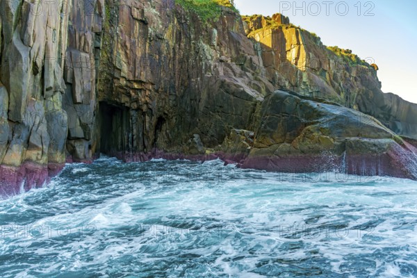 Cliff with a cave in the rough sea of ??Ilhabela on the coast of the state of Sao Paulo, Ilhabela, Sao Paulo, Brazil