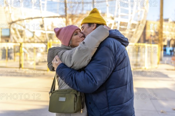 Elderly couple sharing a tender kiss and hug in a festive winter cityscape, celebrating love and togetherness during the holiday season
