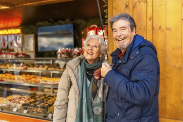 Cheerful senior couple enjoying christmas market, shopping and having fun during winter holidays
