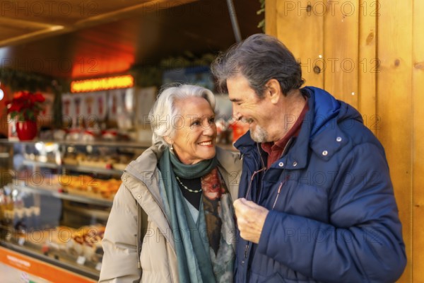 Happy senior couple smiling and enjoying time together during christmas holidays at a winter market